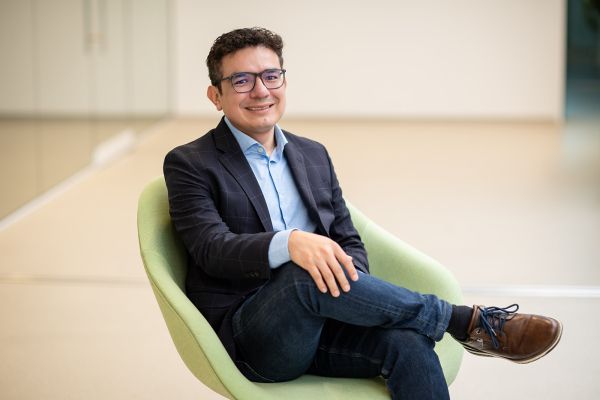A man sitting in a green chair, looking at the camera, smiling