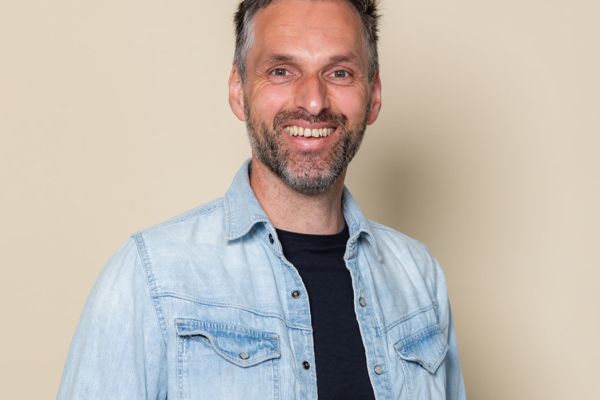 A man with a blue shirt, smiling at the camera