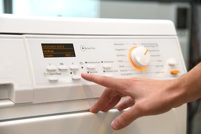 Iemand bedient een wasmachine.