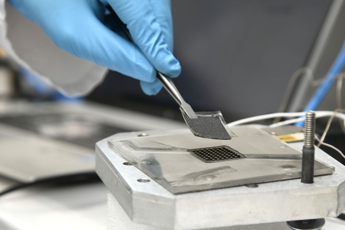 Een hand in een blauwe handschoen in het Hydrogen lab.