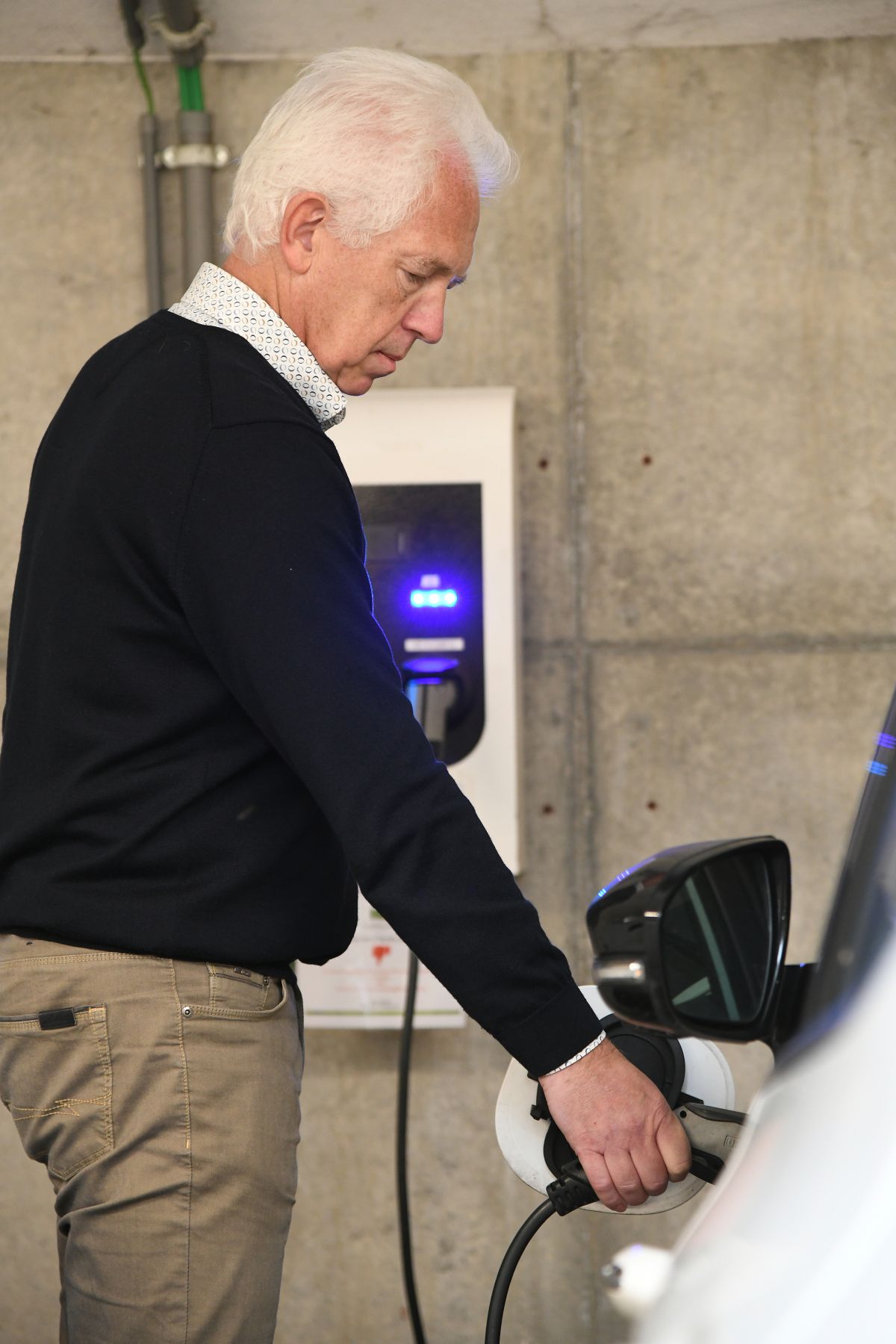 Een man hangt zijn elektrische auto aan de laadpaal.