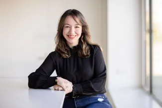 A portrait picture of a woman, looking at the camera and smiling.