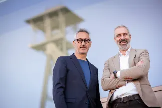 2 men standing in front of the blurred out mine shaft