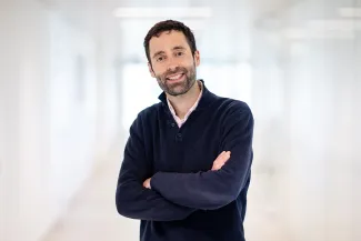A man with his arms crossed, smiling at the camera