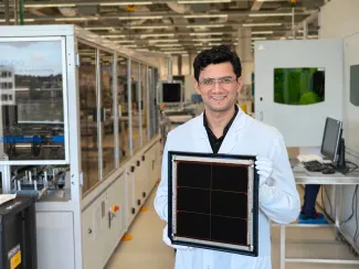 A scientist in a lab coat, holding a demo, smiling