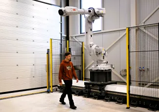 Man wandelt langs de robotarm in het roboticalab.