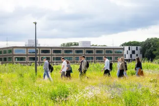 Een groep mensen wandelt door het groen voor het EnergyVille 1 gebouw.
