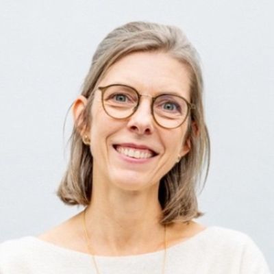 A woman with short hair and glasses, smiling at the camera