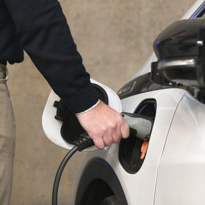 Een man sluit de lader van een elektrische auto aan.